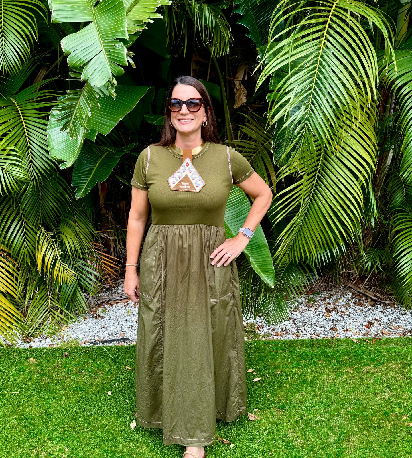 Woman in a green dress standing in front of tropical plants